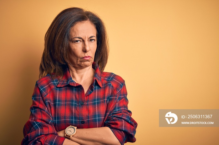 Middle age beautiful woman wearing casual shirt standing over isolated yellow background skeptic and