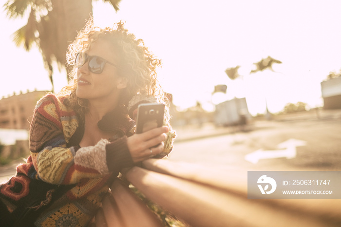 Cheerful beautiful lady enjoyed the leisure activity using modern phone during golden sunset wit dow