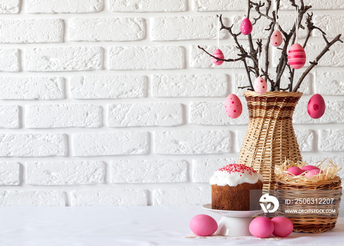 Easter composition with decorated tree branches in a wicker vase, pink colored eggs in wicker basket