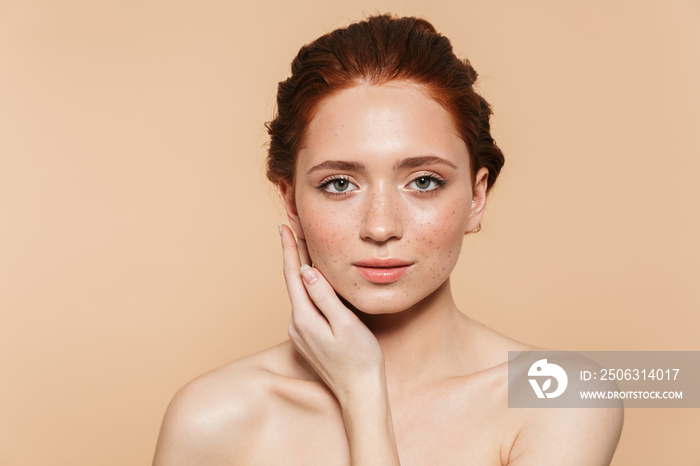 Amazing young redhead woman posing isolated over beige wall background.