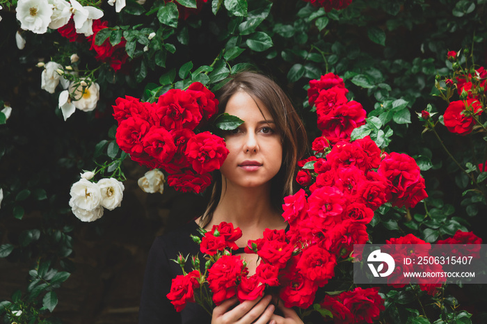 young girl near the bush of red and white roses