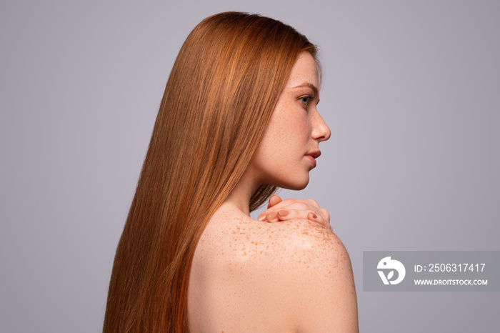 Redhead woman touching freckled shoulder