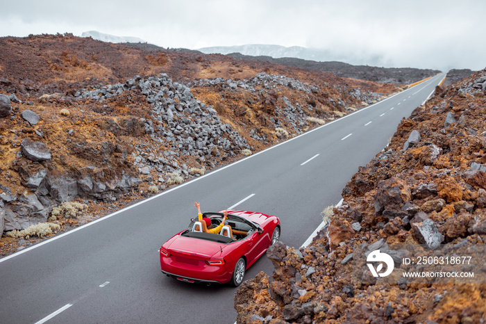 火山谷上美丽的笔直道路上的风景，一位女士开着一辆红色的cabrio