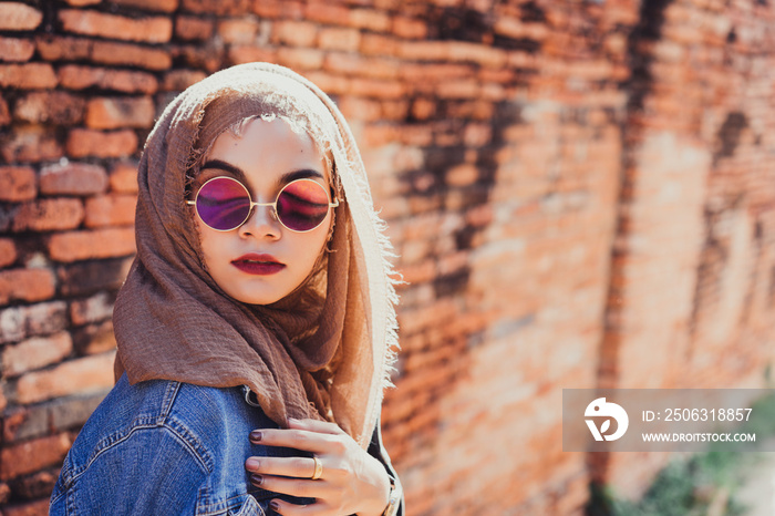 年轻漂亮的穆斯林妇女的时尚肖像和带有复制空间的旧砖墙背景。