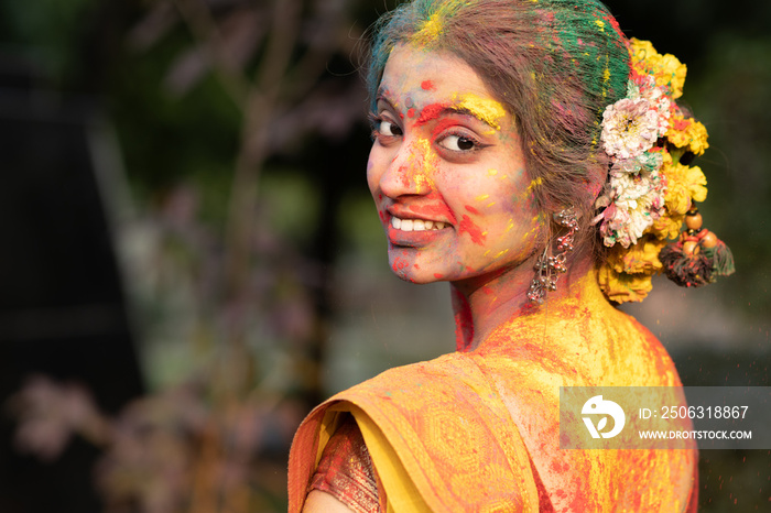 色彩节日holi，年轻漂亮的女孩或女人或穿着印度服装的女士纱丽回头看wi