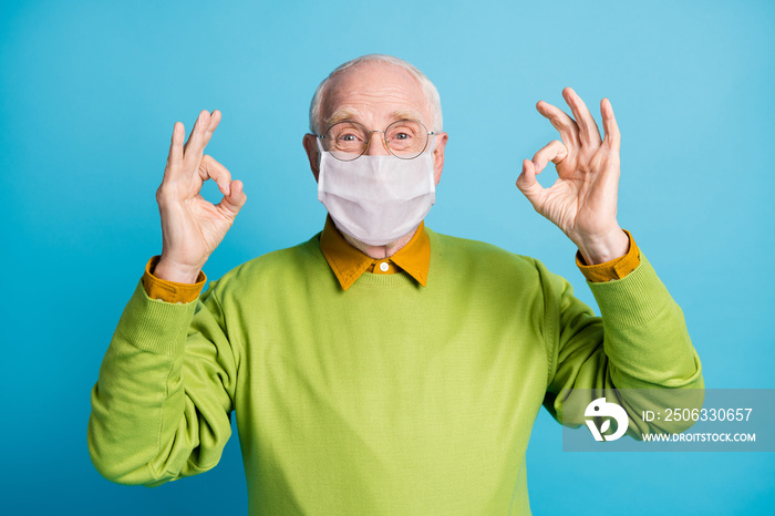 Photo of pensioner raise two arms showing okey wear white face mask isolated blue color background