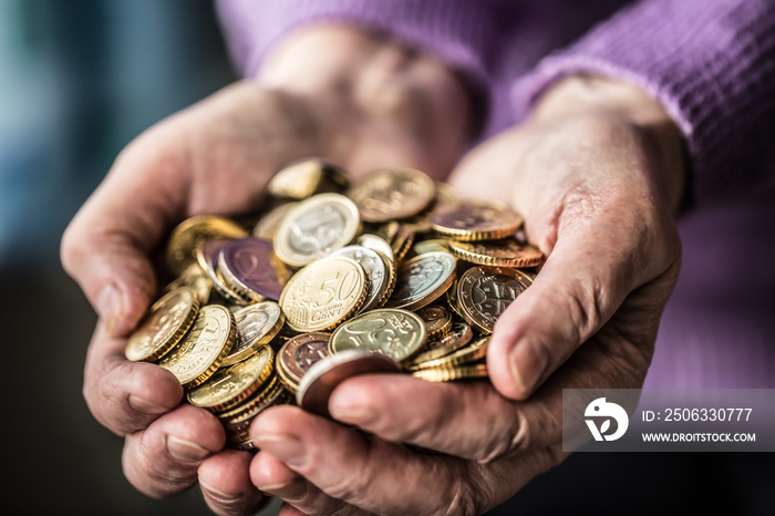 Pensioner woman holding in hands euro coins. Theme of low pensions