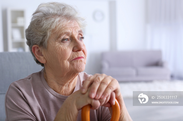 Elderly woman with walking stick at home