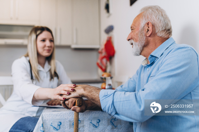 Young positive caregiver taking care of senior man in nursing home