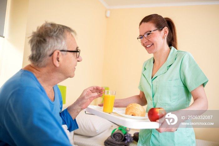 细心的护士在疗养院为老病人提供早餐