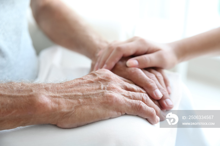 Young woman touching senior man hands, closeup