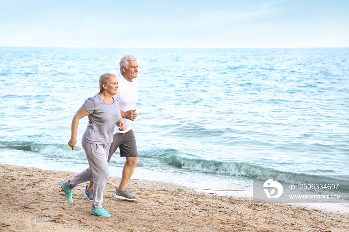 Sporty mature couple running on sea beach