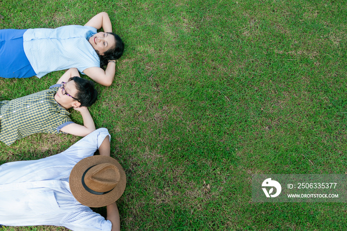 Top view little Asian boy and beautiful middle aged parents relax or sleeping while lying on the gra