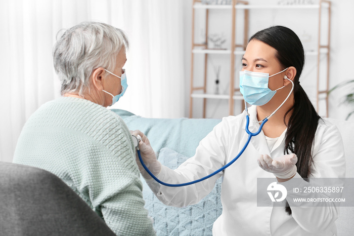 Doctor examining senior woman at home