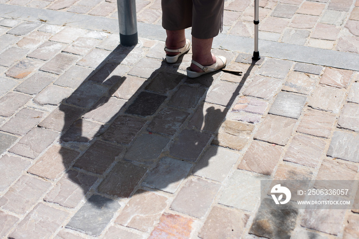 Shadow and legs of an elderly woman with a walking aid