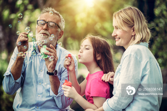 Happy family blows soap bubbles together while going vacation on weekend in the garden park in summe