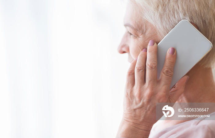 Close up of mature retired woman talking by smartphone