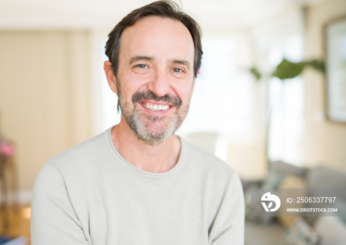 Handsome middle age man smiling looking at the camera at home