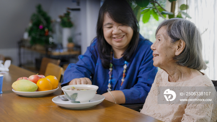 Mothers day ,Daughter feeding elderly mother with soup.