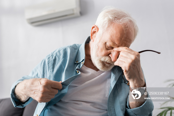 Tired elderly man feeling hot in living room