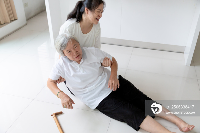 Asian elderly people with walking stick on floor after falling down and caring young woman assistant