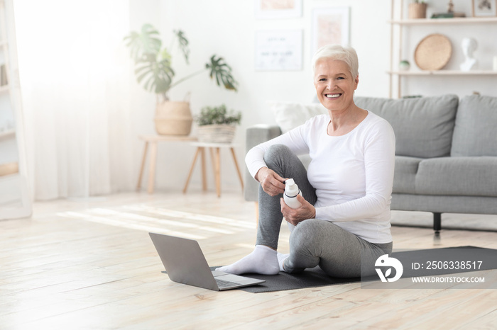 健康的生活方式。积极的老年女性在家用笔记本电脑锻炼时摆姿势
