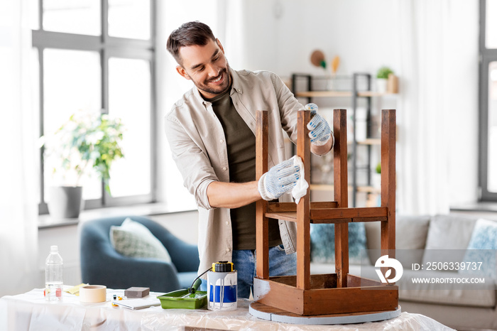 renovation, diy and home improvement concept - happy smiling man degreasing old wooden table or chai