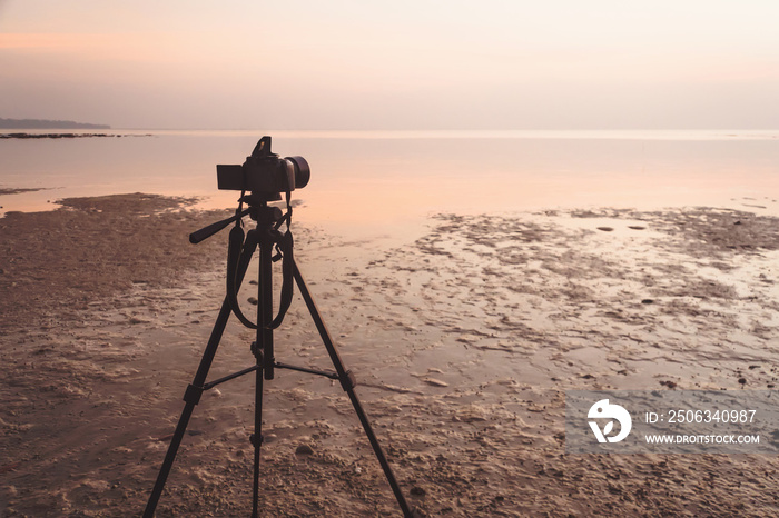 相机设置在三脚架上，拍摄日出或日落时刻的照片或视频
