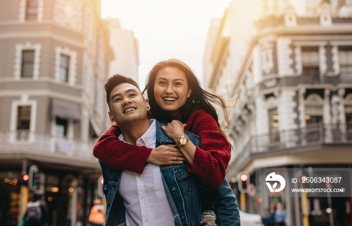 Asian couple piggybacking on city street