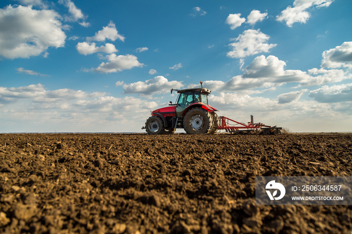 Farmer in tractor preparing land with seedbed cultivator as part of pre seeding activities in early 