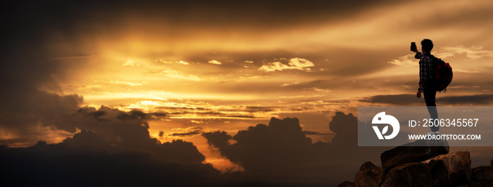 Silhouette of Hikers climbing up mountain cliff in sunset selfie with smartphone. Concept of limits 