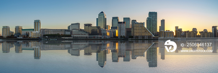 Panorama of Canary Wharf business district with water reflection at sunset