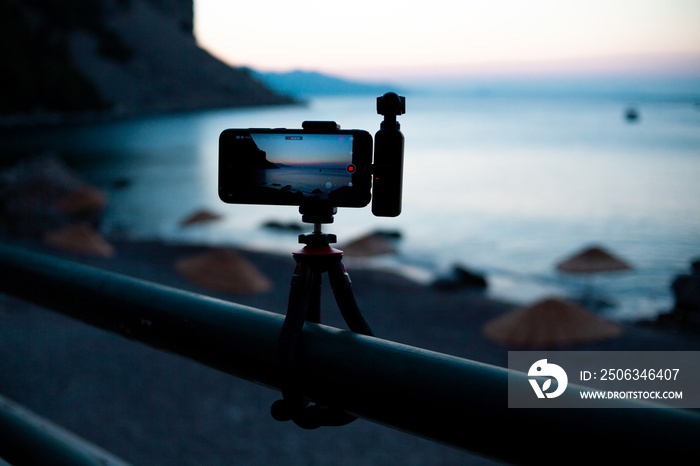 安装在三脚架上的便携式相机的手机，拍摄海湾上空的日出。拍摄视频时间