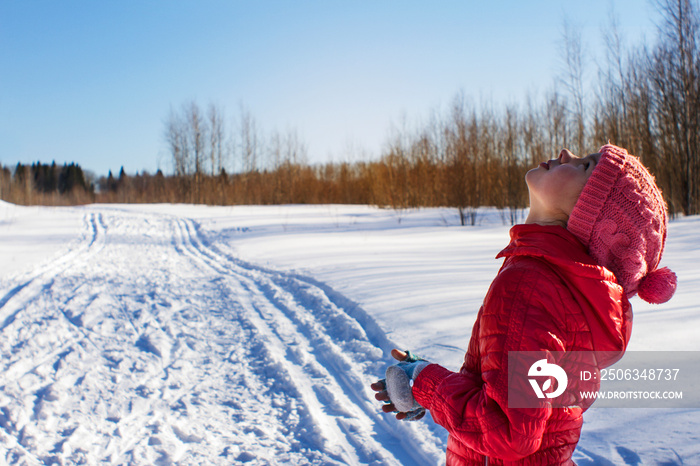 晴天，女孩站在白雪覆盖的田野上抬头看