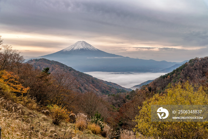 美丽的富士山在秋天的树木颜色季节。下面的川口镇和湖泊被覆盖