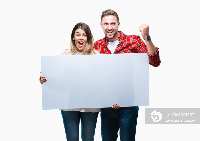 Young couple together holding blank banner over isolated background screaming proud and celebrating 