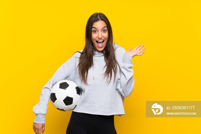 年轻的足球运动员女性，背景为孤立的黄色，面部表情震惊