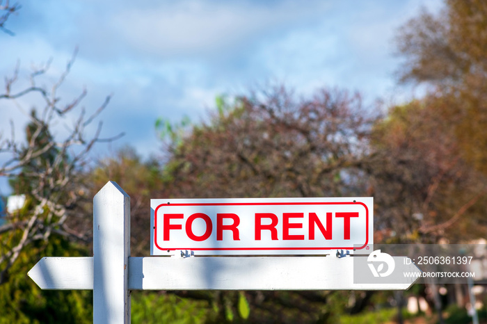 For Rent real estate sign. Blurred sky and trees background