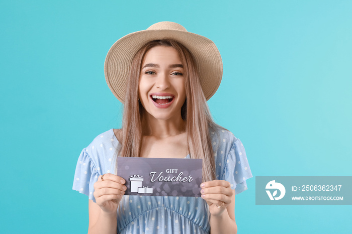 Beautiful young woman with gift voucher on color background