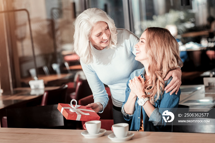 Surprise. Emotional positive young woman looking happy while getting an unexpected present from her 