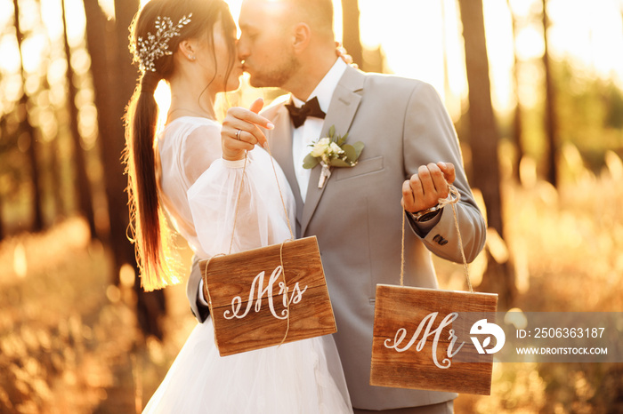 Wonderful wedding couple in the forest at sunset. Mister and Missis.