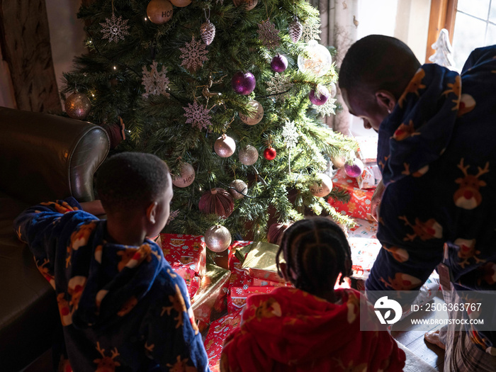 Father looking at Christmas presents with sons at home