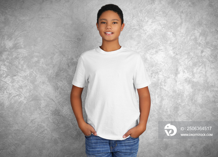 年轻的非裔美国男孩穿着白色t恤，靠着纹理墙站着