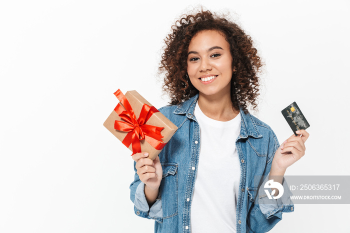 Happy young african woman posing isolated over white wall background holding present gift box and cr