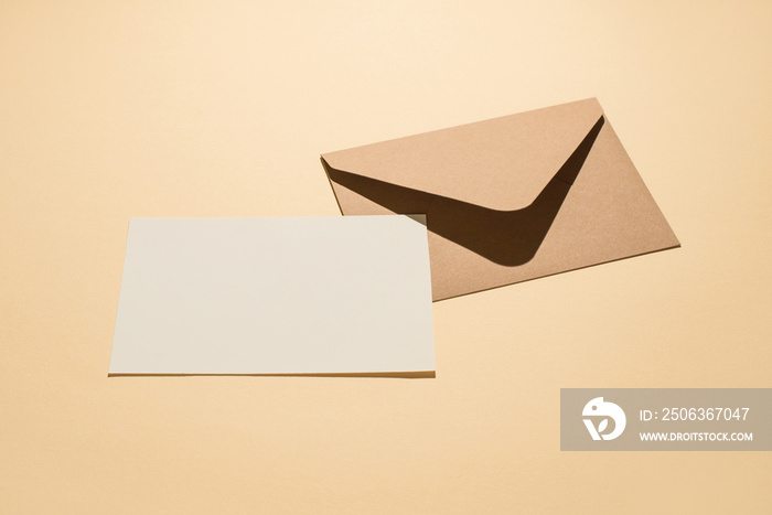 Top view photo of craft paper envelope and white paper card on isolated beige background with blank 