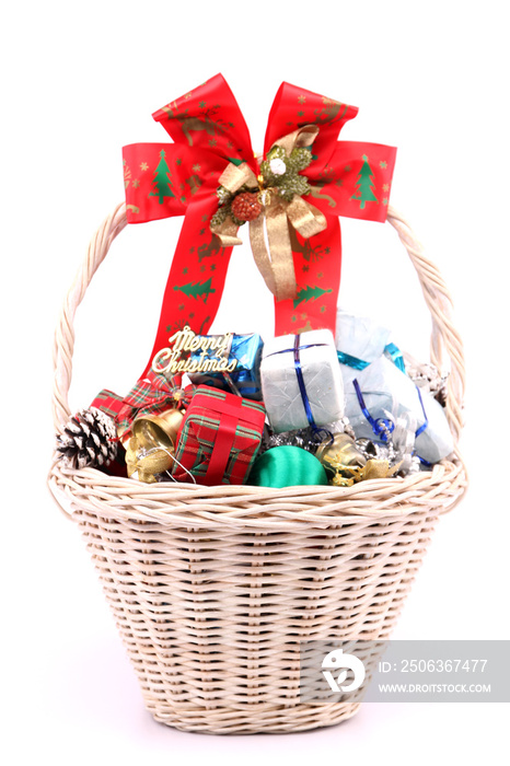 Gifts and decorations in a basket on Christmas Eve with white backdrop.