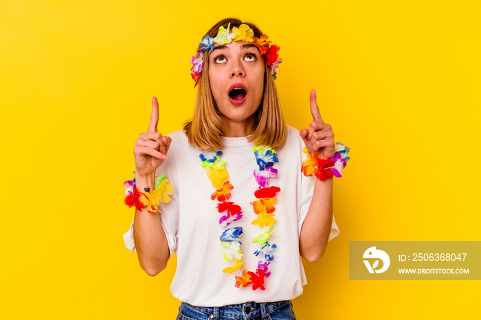 Young caucasian woman celebrating a hawaiian party isolated on yellow background pointing upside wit