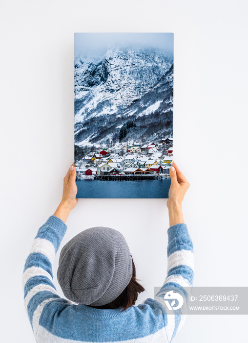 Girl hanging white canvas on wall