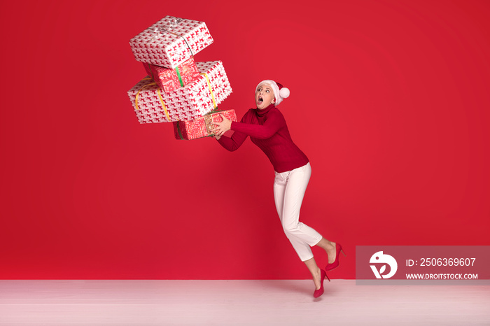 Mature woman in red santa claus hat with gifts.