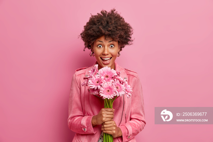 惊讶快乐的非洲发型年轻女子收到陌生人的鲜花，震惊不已，收到了快递。